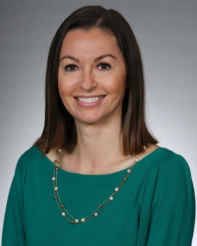 Corporate headshot woman in teal sweater layered pearl and gold chain necklace