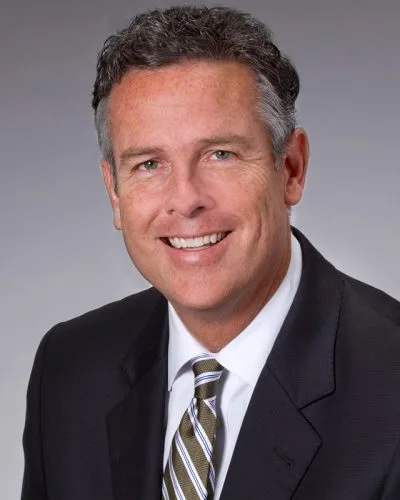 business headshot man dark suit striped tie confident smile gray backdrop