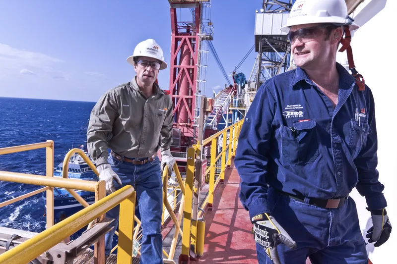 Corporate portraits of two BHP Billiton drilling supervisors in hard hats on offshore platform