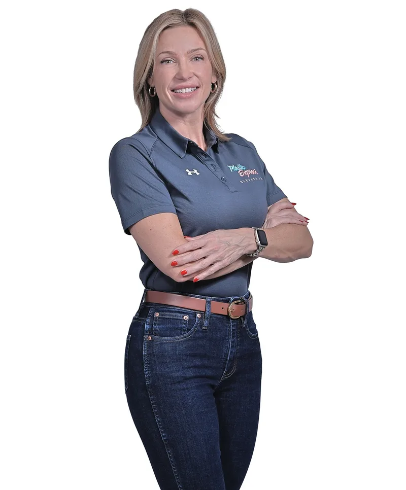 Corporate headshot woman in branded grey polo arms crossed smiling