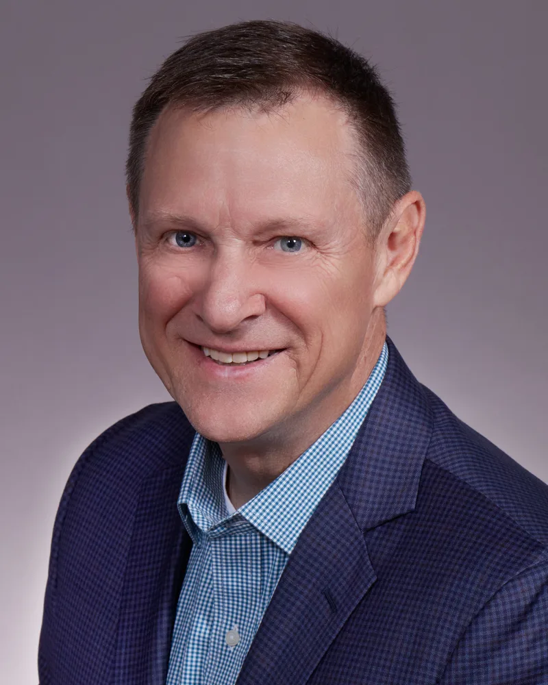 Corporate headshot portrait man navy blazer blue checkered shirt smiling