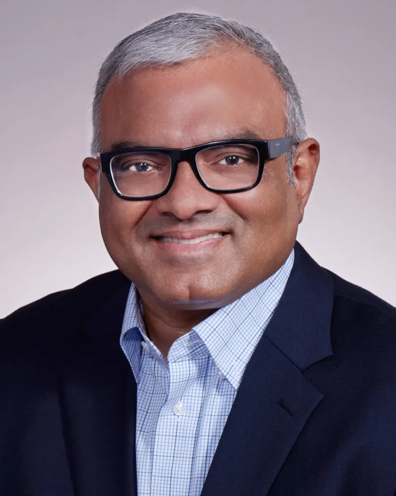 Corporate headshot portrait of smiling professional man wearing dark blazer