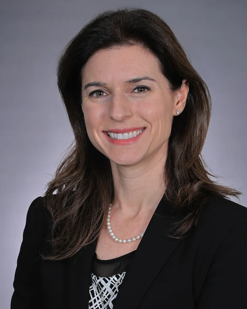 Corporate headshot portrait woman dark hair pearl necklace black blazer