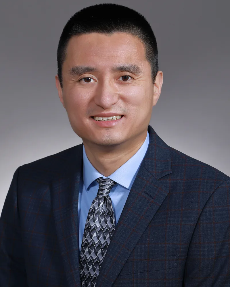 Professional male corporate headshot in navy plaid suit and gray tie