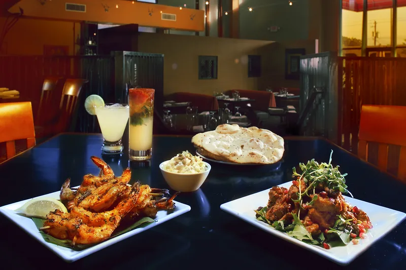 Grilled shrimp kebabs, corn raita, naan, and Kashmiri chicken restaurant spread
