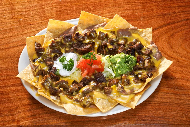 Nachos Fajita topped with carne asada melted cheese guacamole sour cream tomatoes