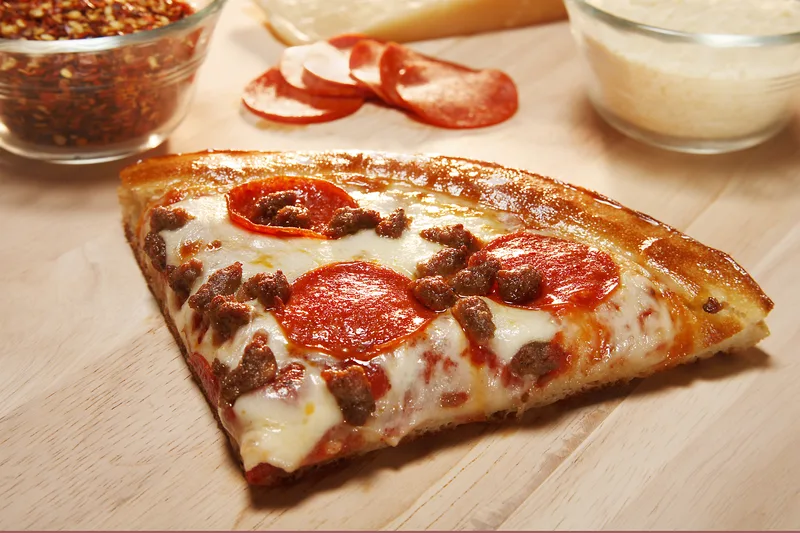 Pan pizza slice with pepperoni ground sausage bubbling mozzarella golden crust