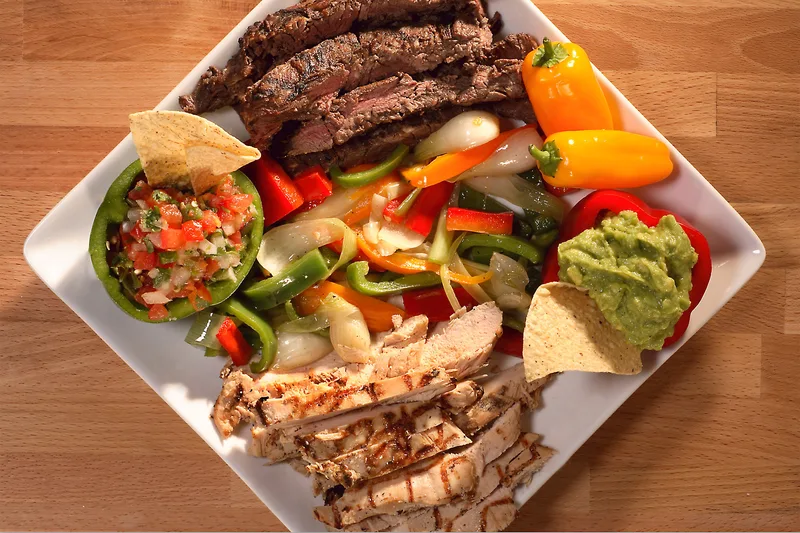 Fajitas platter with skirt steak, grilled chicken, sautéed bell peppers, guacamole