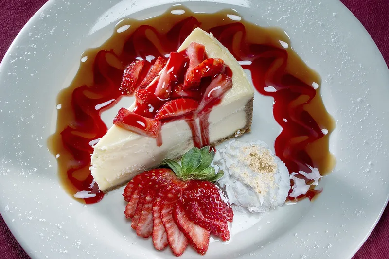 Desserts strawberry cheesecake slice with caramel drizzle fresh berries whipped cream