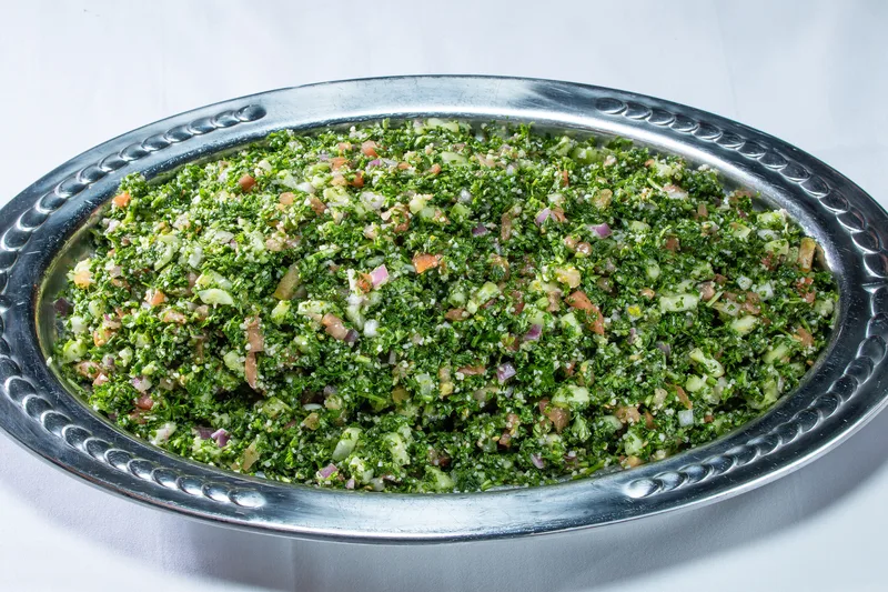 Tabbouleh salad heaped on polished stainless steel oval serving platter