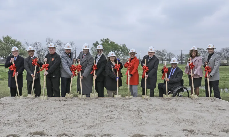 corporate group portrait at outdoor groundbreaking ceremony holding gold shovels
