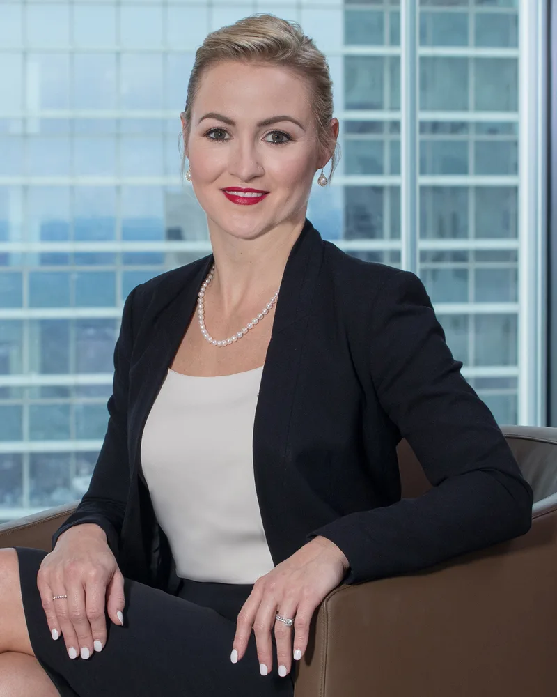 Lifestyle executive portrait woman black blazer pearl necklace city skyline background