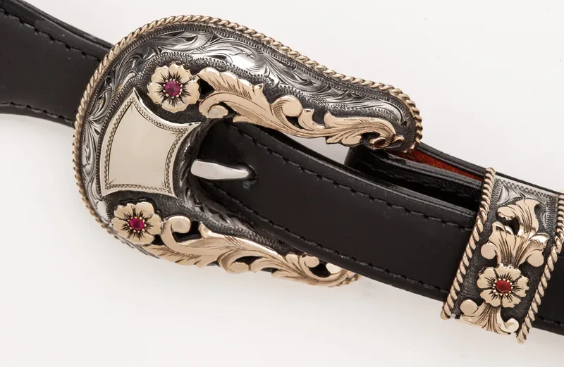 ornate engraved silver and gold Western belt buckle with ruby floral accents