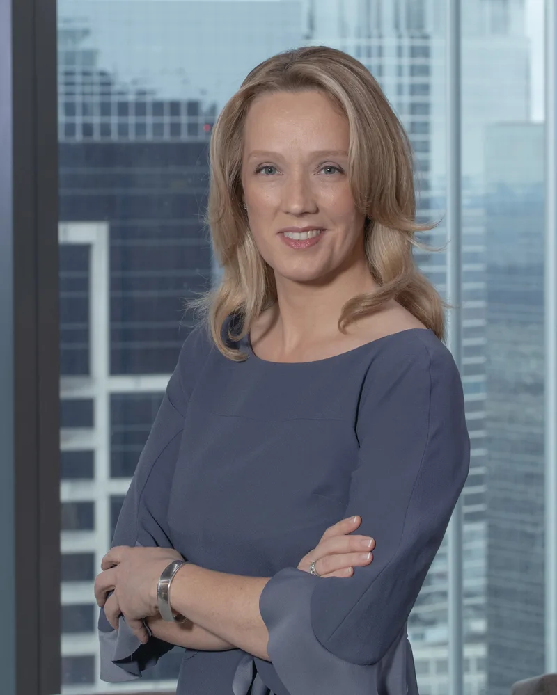 corporate headshot professional woman gray blouse arms crossed city skyline backdrop