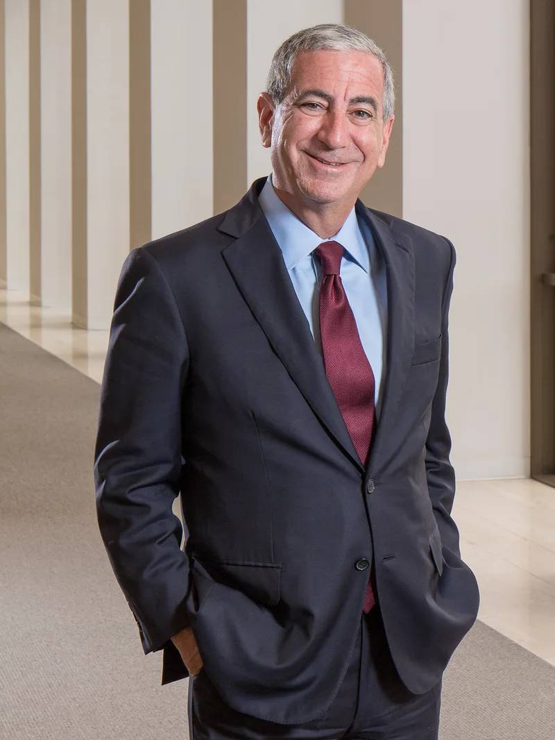 Corporate headshot of smiling executive in charcoal suit and burgundy tie